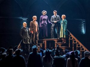 Five castle members of Harry Potter and the Cursed Child standing on a staircase on stage.