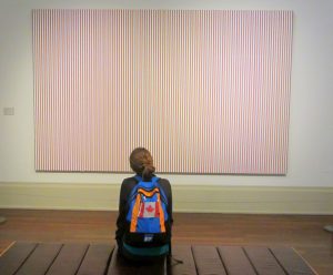 A girl with a small backpack enjoys a large painting on the wall
