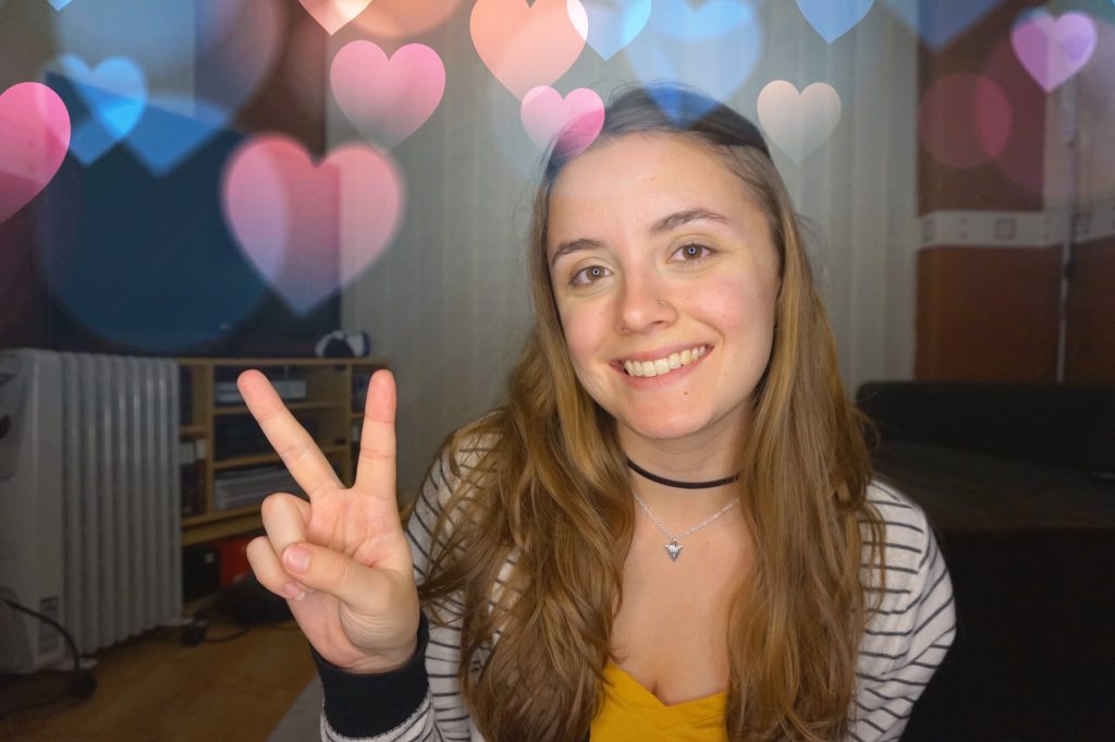 A girl smiling and holding up the peace sign in her living room