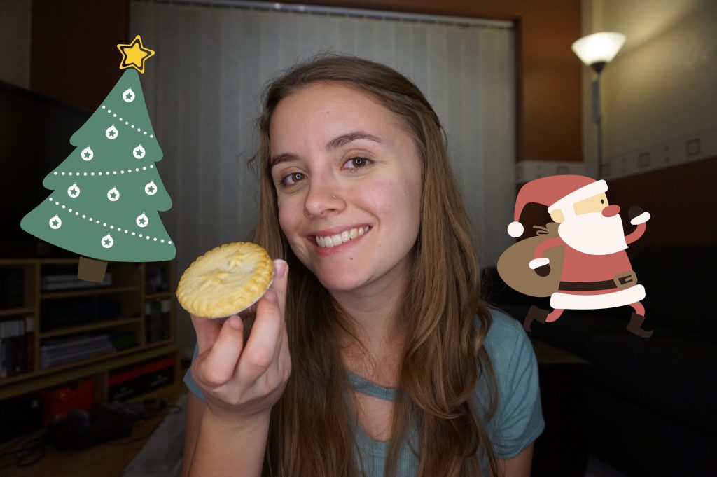 A girl smiling and holding a mince pie in her living room