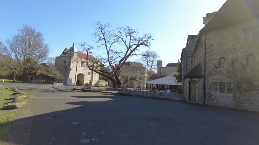 Stone buildings, bare-branched trees and an open paved area at Aylesford Priory