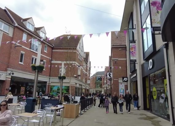 A Canterbury shopping street with shopfronts, bunting and outdoor cafe tables.