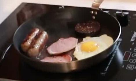 Sausages, bacon medallions, black pudding and a fried egg sharing a frying pan