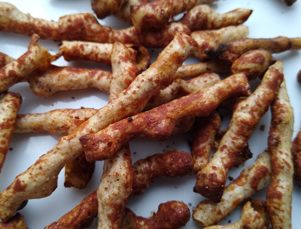 Irregular brown Twiglet sticks shown close up on a light surface