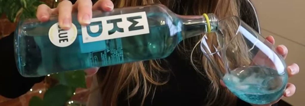 WKD Blue being poured from a labelled bottle into a glass