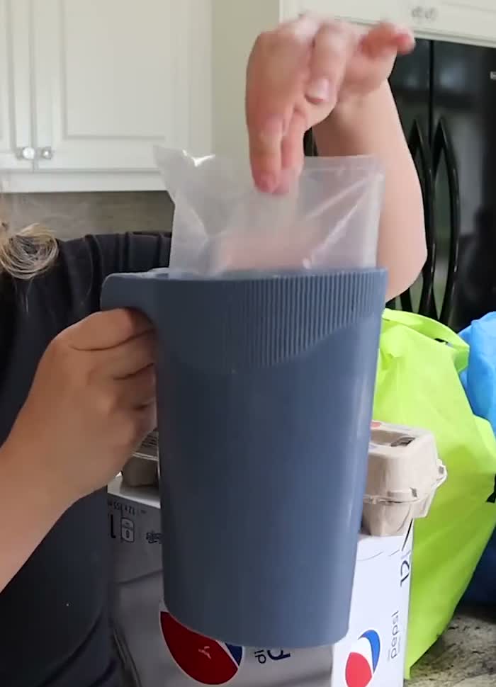 Milk bag sitting in a blue plastic holder, with hands demonstrating it