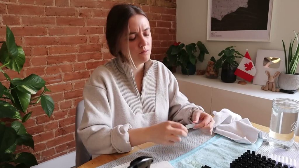 Alanna applying a small label at a table beside rows of perfume sample bottles