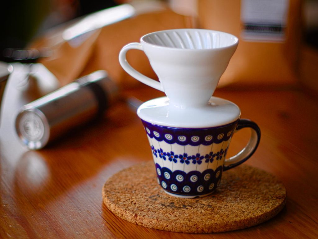 A white V60 coffee cone resting on a patterned mug