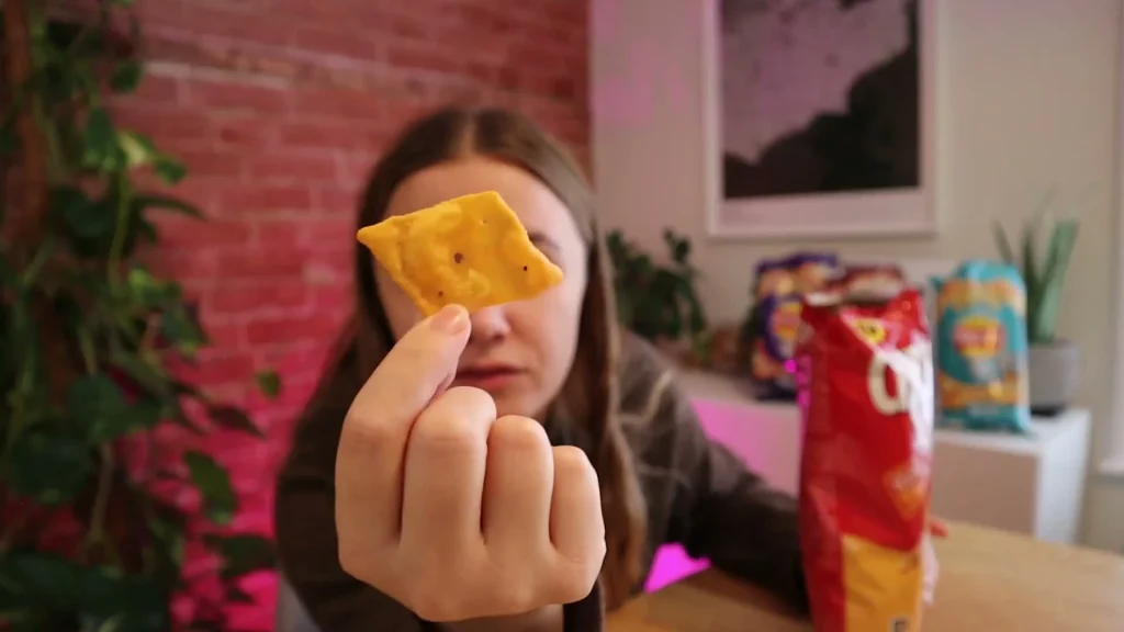 Alanna holding a thin orange Cheez-It Snapped snack close to the camera.