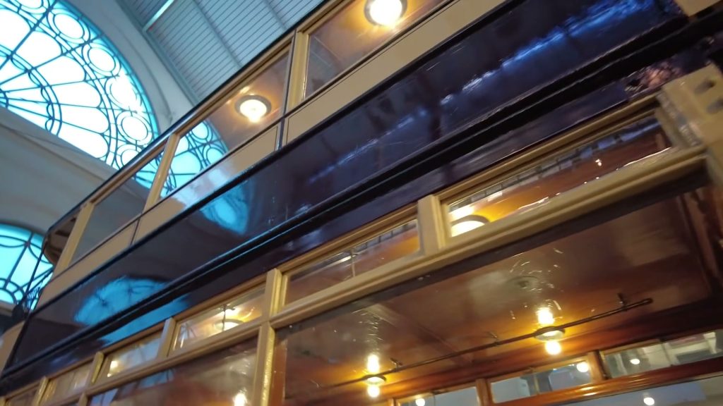 Navy and yellow tram body with wooden window frames and lights inside