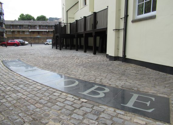 Cobblestone courtyard with parked cars, surrounding buildings and a ground marker reading The Globe
