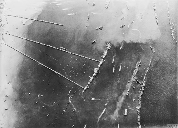 Aerial black and white photograph of Mulberry B harbour, with long roadways leading from the beach to offshore piers.