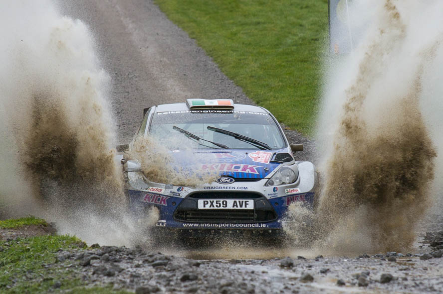 A Ford Fiesta rally car splashing through water at Wales Rally GB.