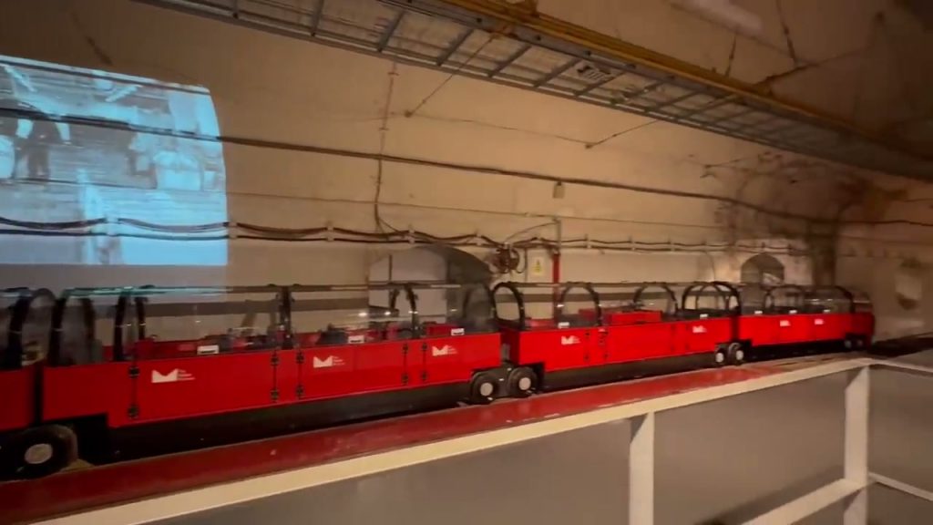 Small red passenger carriages parked at Mail Rail.