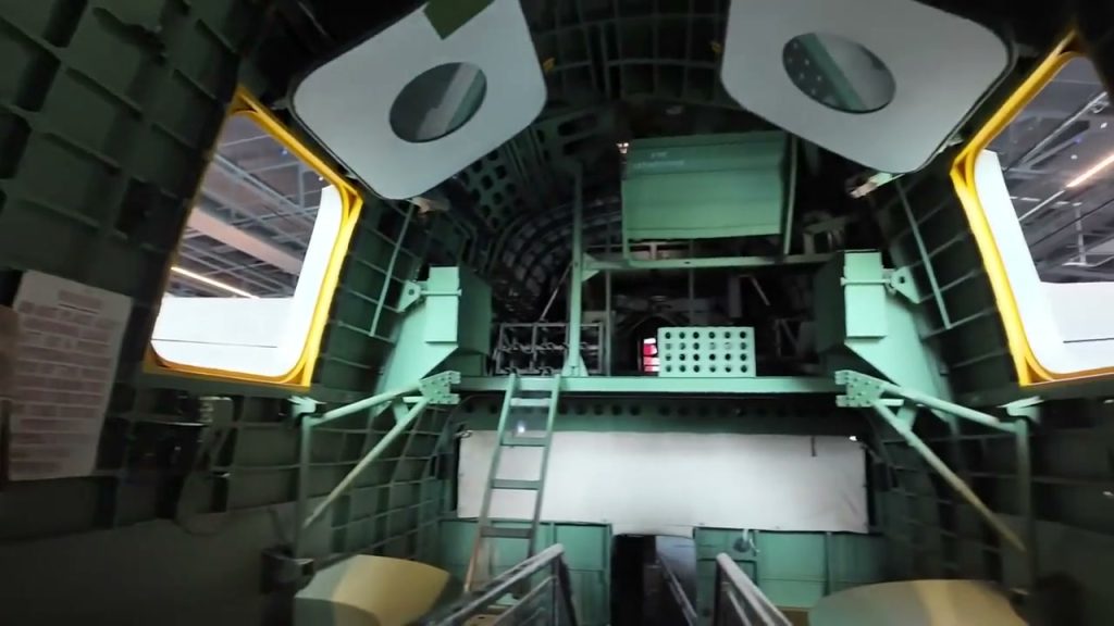 Green aircraft interior with a ladder and open hatches at the RAF Museum.
