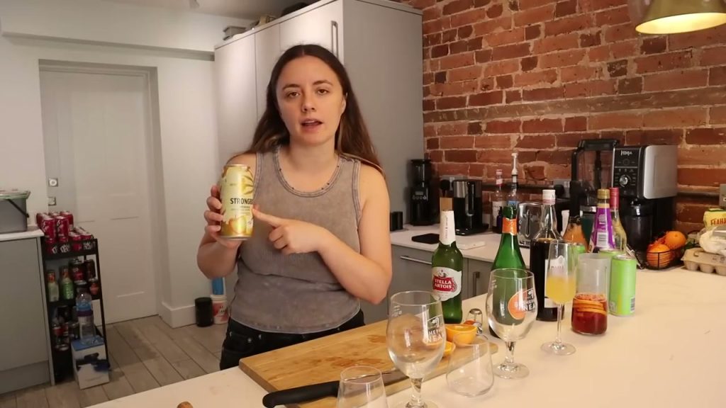 Alanna holds a Strongbow can beside bottles and glasses on the kitchen counter.
