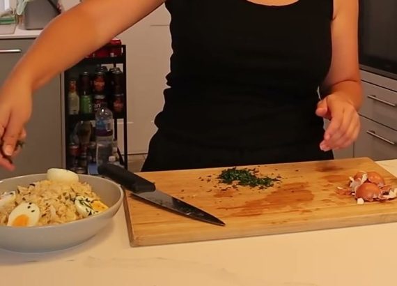 Alanna adds parsley to a bowl of pale kedgeree topped with hard-boiled egg pieces.